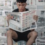 concentrated ethnic man reading newspaper at home